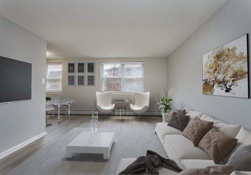 Light colored living room with beige couch and tan pillows. 白色咖啡桌和老式椅子.